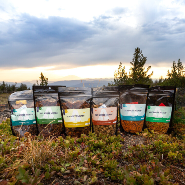 
                  
                    All six of the the Alt Route Meals pictured side by side standing on the ground. 
                  
                